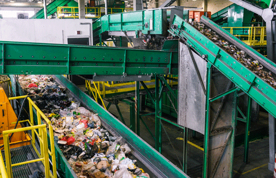 In the picture, there is a conveyor belt at a waste treatment plant transporting waste.